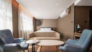 A hotel room with a bed, two armchairs, a small round table, and a lamp. - Homeinn · neo (Xi'an Zhonglou Subway Station) (Xi'an)