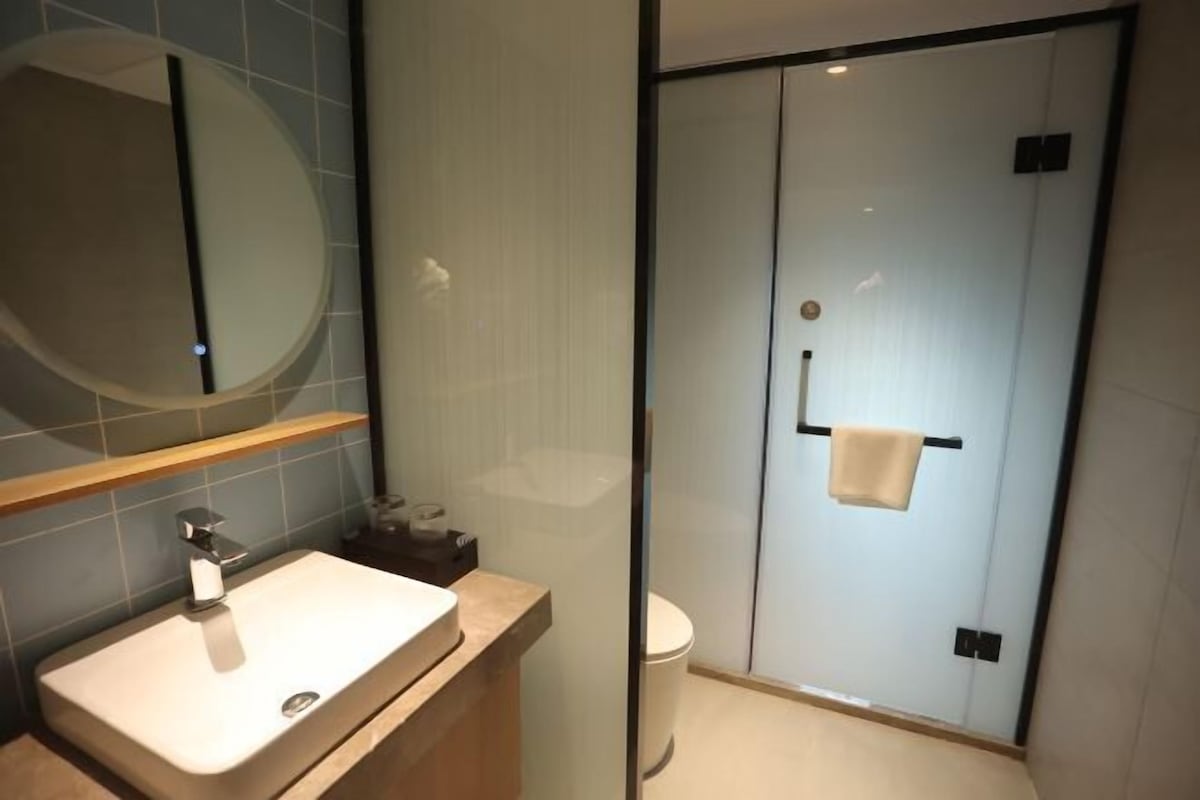 A modern bathroom with a sink, mirror, and glass shower enclosure.
