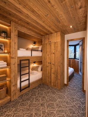 A wooden interior with bunk beds, a ladder, shelves with towels, and a window with a view. - Exceptional, renovated duplex for 6–8 people (Val d'Isère)