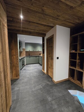 A spacious room with a wooden ceiling, a built-in bookshelf, and a view into a kitchen area. - Exceptional, renovated duplex for 6–8 people   (Val d'Isère)