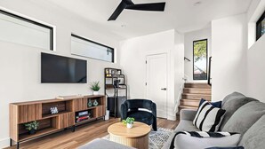 A modern living room with a flat-screen TV, wooden entertainment unit, and a round coffee table.