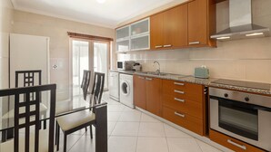 Une cuisine moderne avec des meubles en bois, un four encastré et un lave-linge.