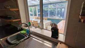 Een keuken met uitzicht uit het raam, een spoelbak en een messenblok.