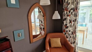 Een kamer met een leren fauteuil, een grote spiegel en hanglampen.