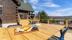 A wooden deck with a table set for a meal, outdoor chairs, and a view of the surrounding landscape. - Secluded w/ Deck Views, Hot Tub, & Ping Pong Hudson in the Berks by Avantstay (East Chatham)