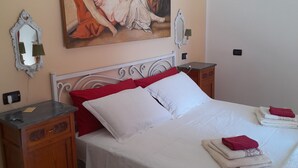 A bedroom with a bed, two nightstands, a mirror, and a painting on the wall. - DUETERRE ROOM & HOST (Amelia)