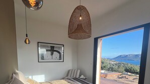 Een slaapkamer met een groot bed, een hanglamp, een rieten plafondlamp, een lijst met een afbeelding, en uitzicht op de omgeving.