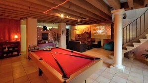A pool table in a room with wooden beams, a staircase, and a projector screen. - Le Moulinois - GLEIZE (GLEIZE)