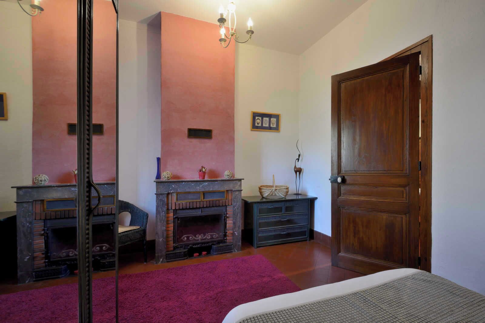 Ein Zimmer mit Kamin, Holztür und rotem Teppich.
