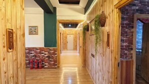 Un pasillo de madera con una pared de ladrillo, una puerta con el número 20 y un extintor.