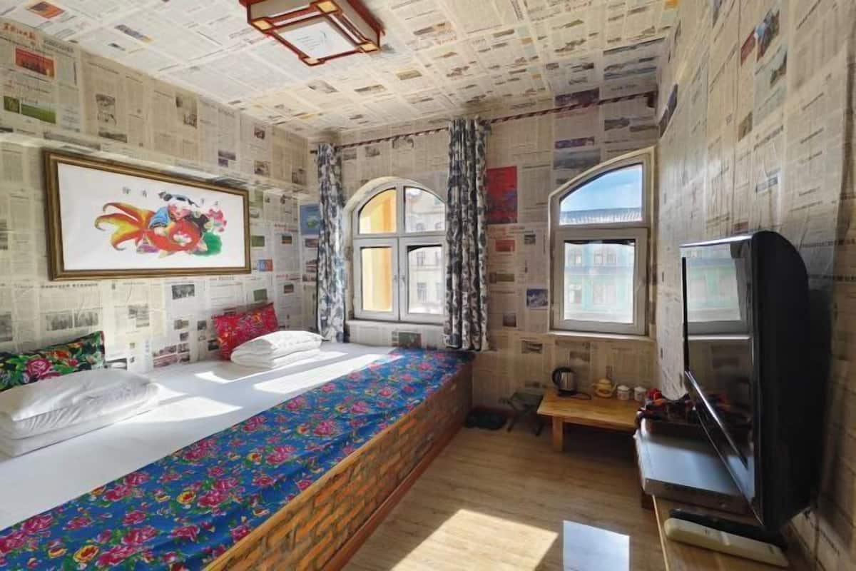 A room with a bed, a television, and a window.