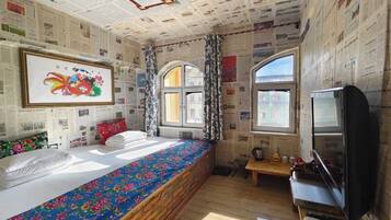 A room with a bed, a television, and a window.