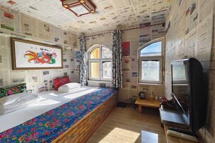 Una habitación con una cama, televisión y ventana.