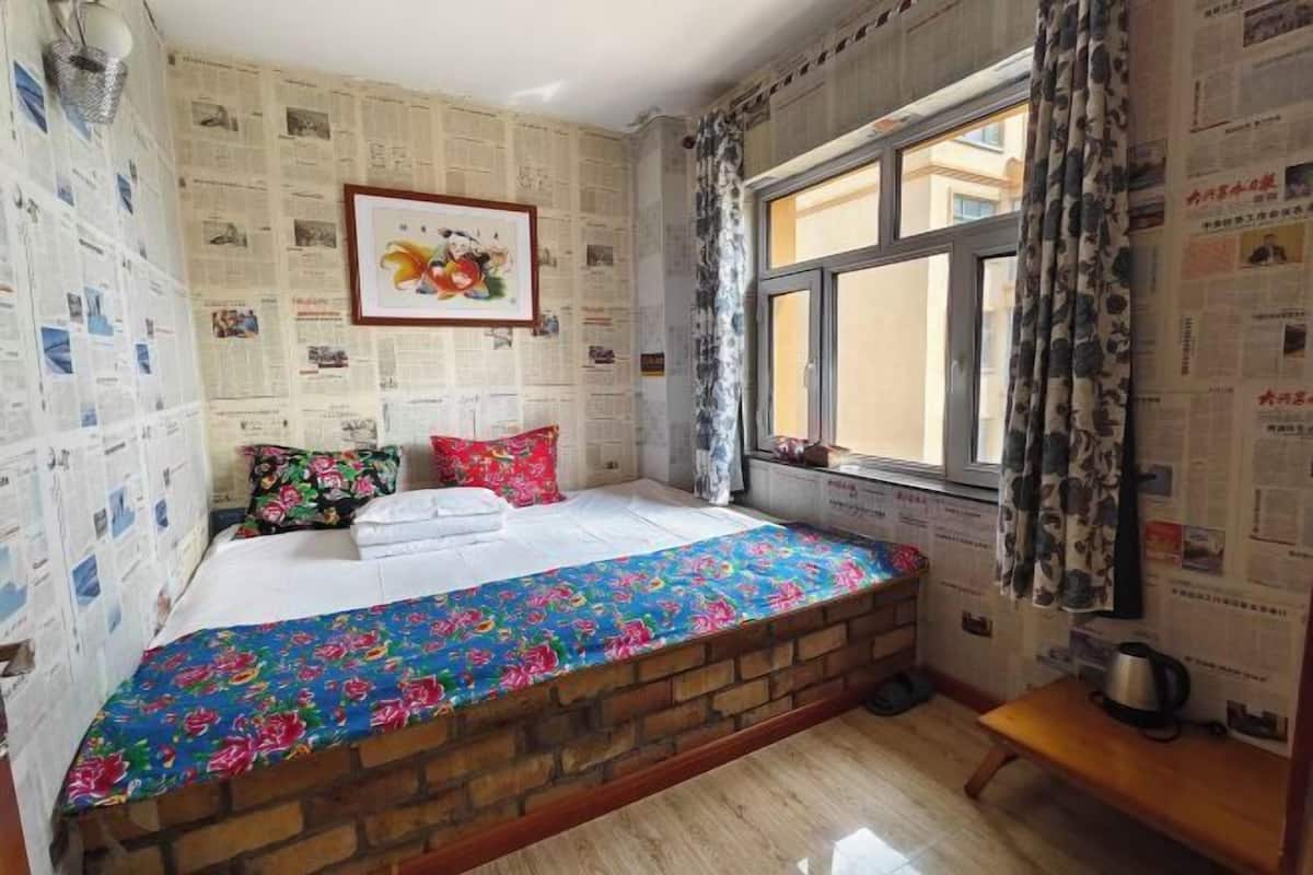 A room with a bed, a window, and a brick wall.