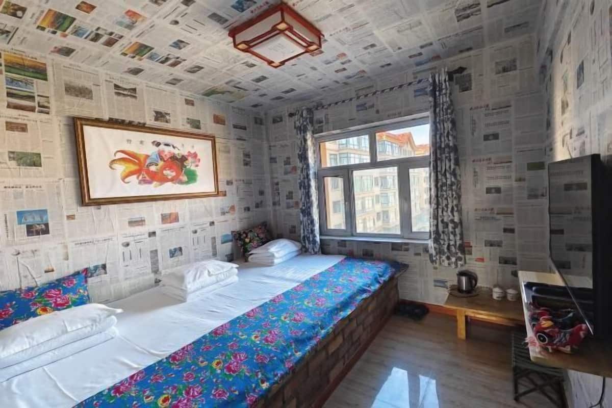 A room with a bed, a window, a painting, and a wooden bench.