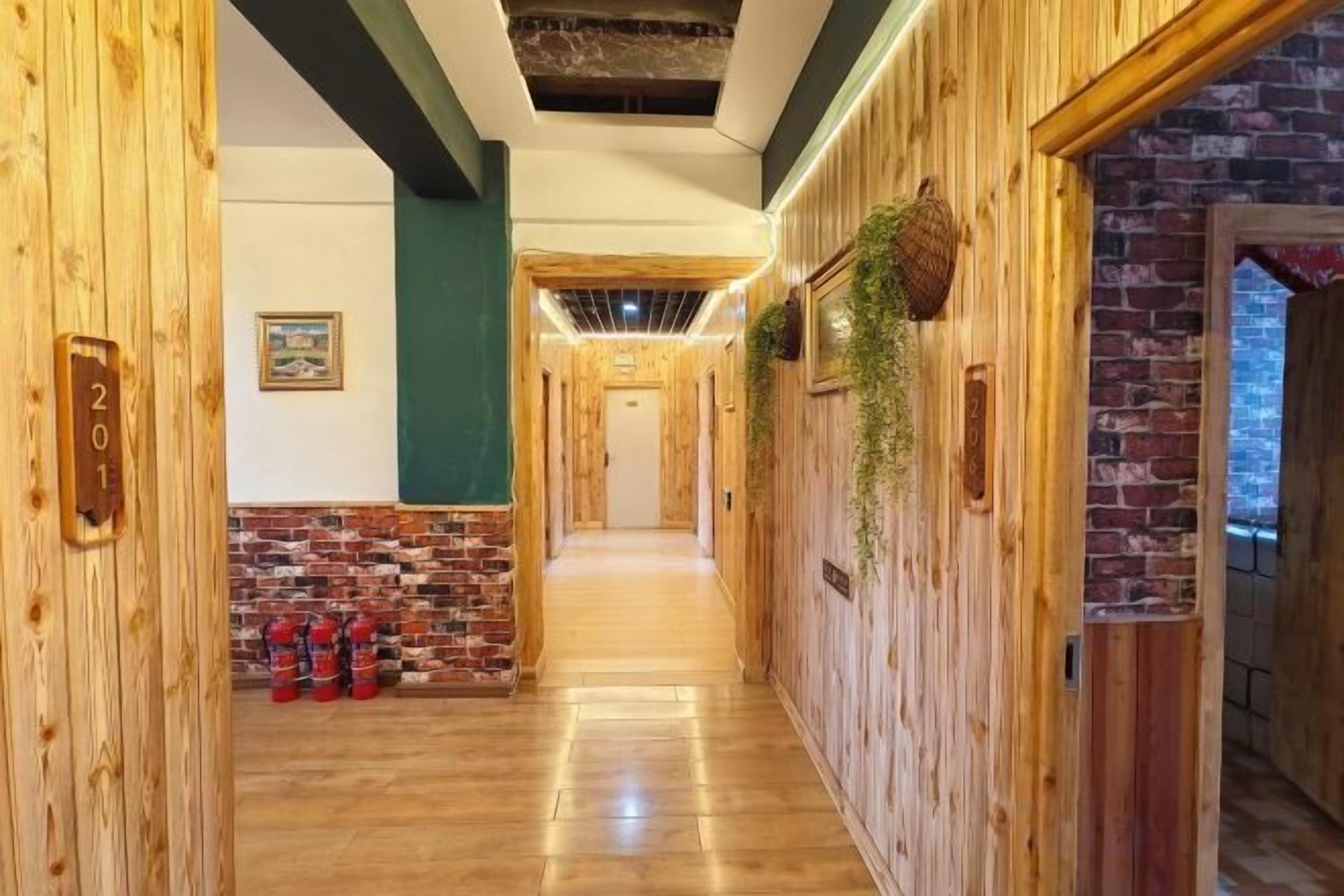Un pasillo de madera con un detalle de pared de ladrillo, una placa con un número y una planta.