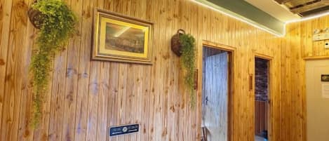 Un interior de madera con un cuadro enmarcado, un letrero y plantas colgantes.
