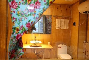 Un baño de madera con lavamanos, espejo, toallero y retrete.