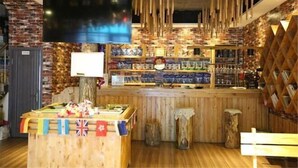 Una zona de bar con estantes de madera, un televisor montado en la pared y un mostrador de madera con banderas.
