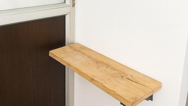 A corner with a white door, a dark wooden panel, and a wooden shelf mounted on the wall. - Room AREAS by QuBeLab (Bello)