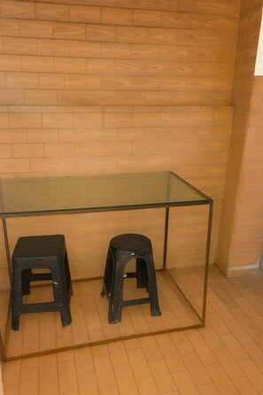Una habitación con pared de ladrillo de madera, una mesa con cubierta de vidrio y dos taburetes negros.