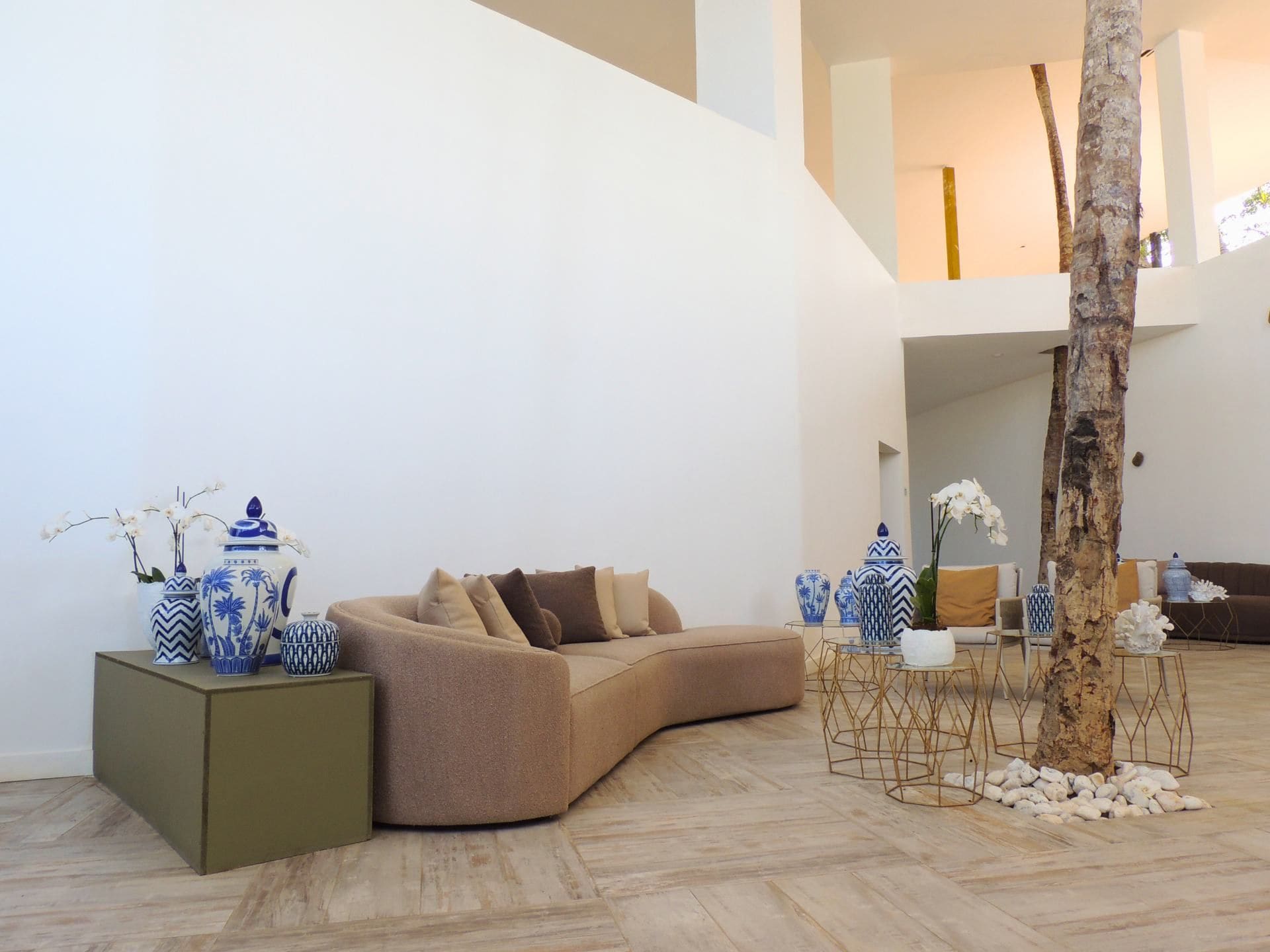 A modern living room with a curved sofa, decorative vases, and a tree trunk centerpiece.
