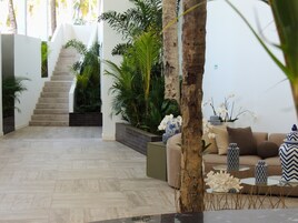 A modern interior with a staircase, indoor plants, a sofa set, and decorative vases.