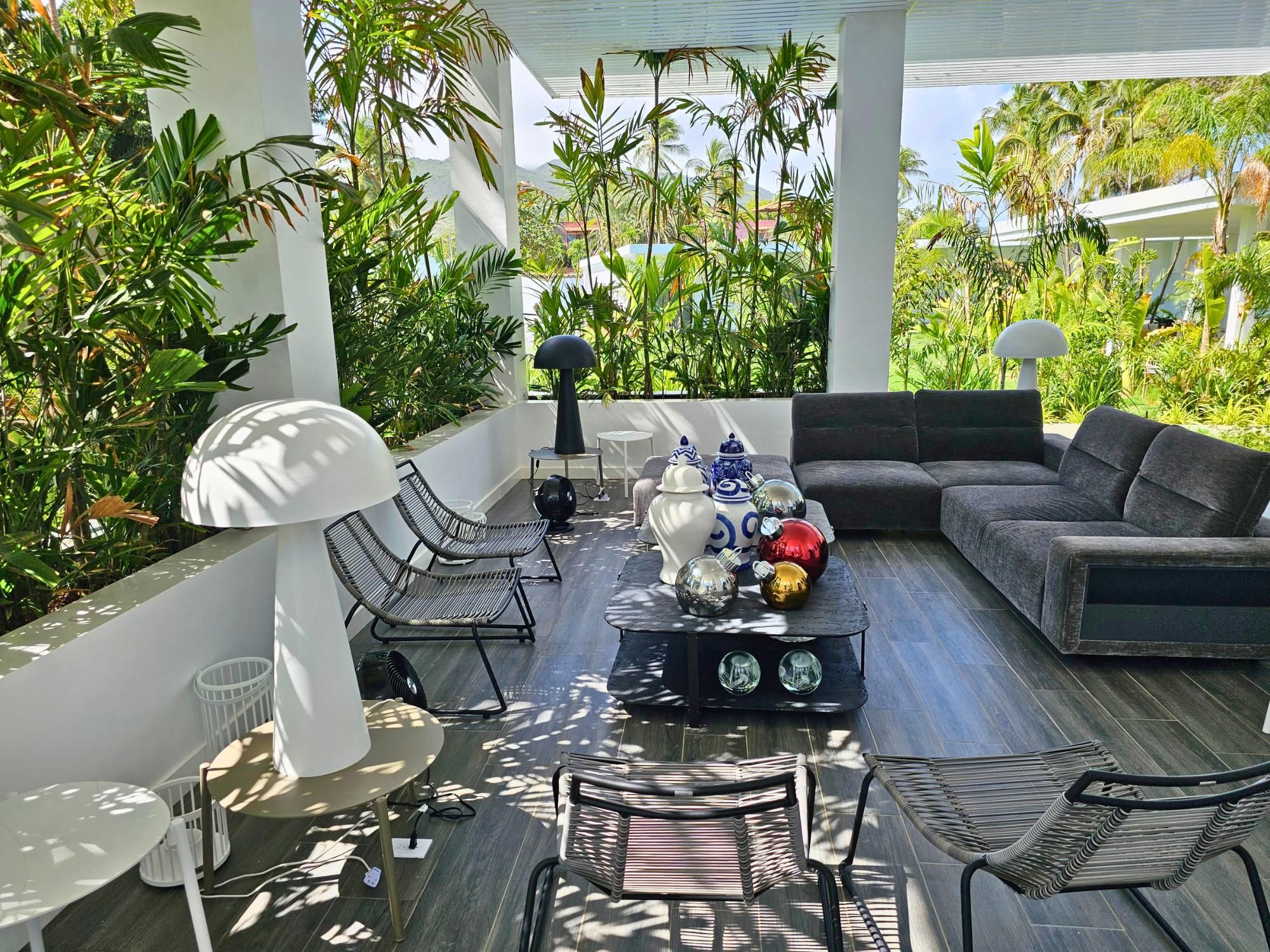 Un espacio exterior moderno con un sofá, sillas y una mesa de centro.