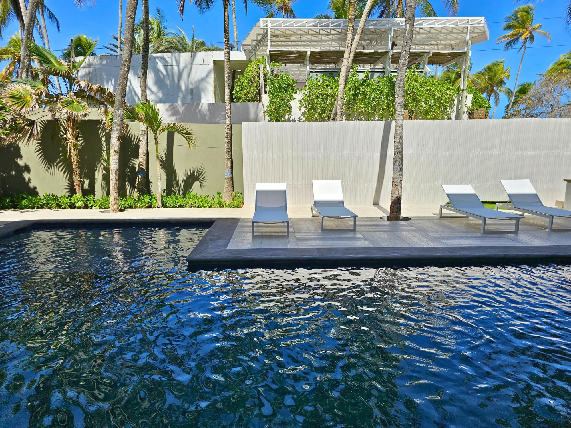 A pool area with lounge chairs and a modern building in the background.