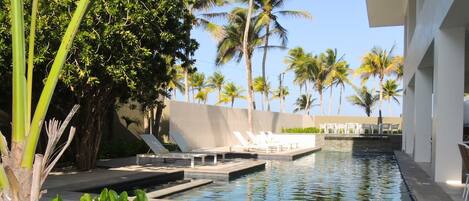 A pool area with lounge chairs and palm trees.