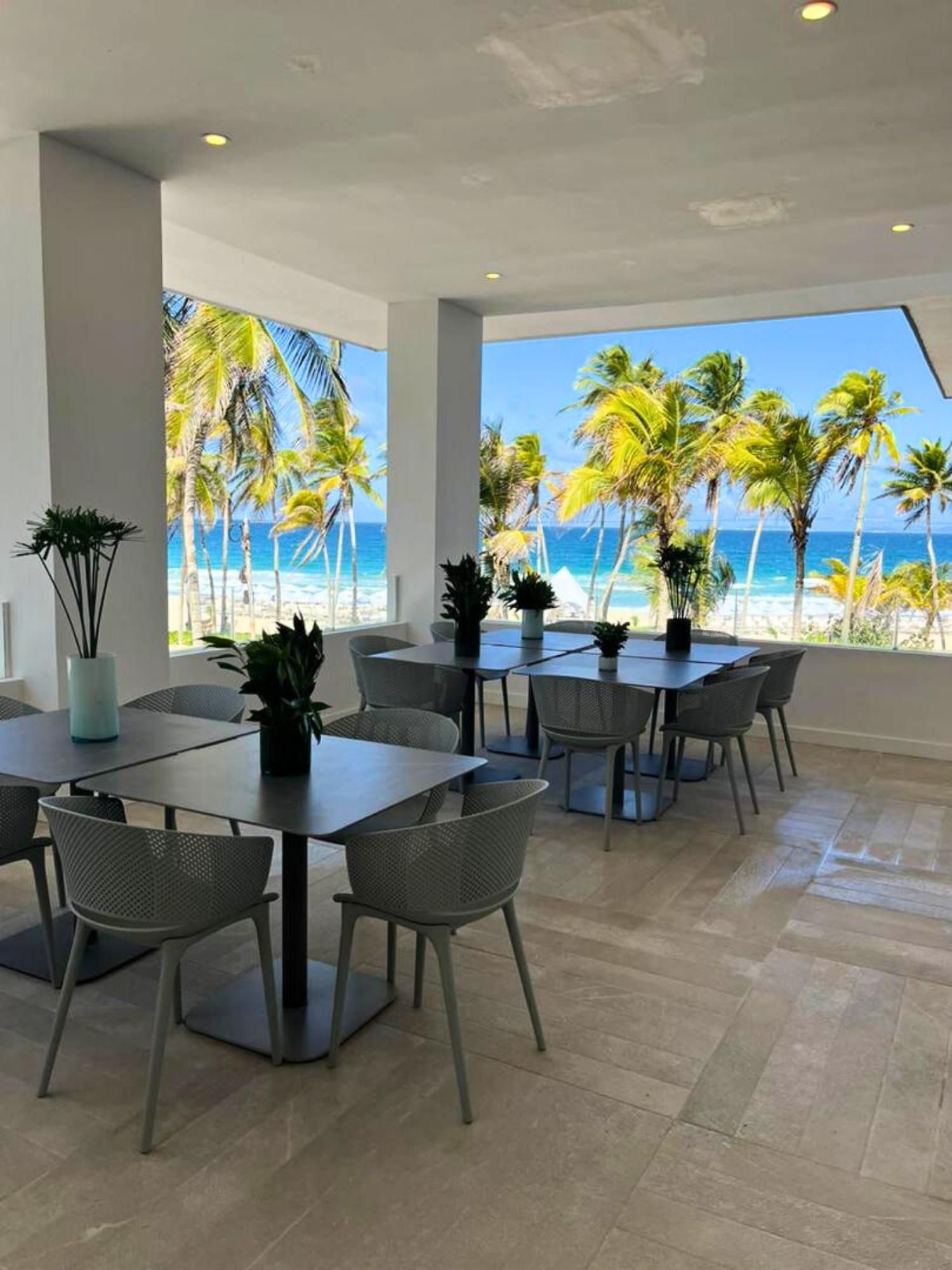 A spacious dining area with a view of the beach and palm trees.