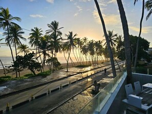 A beachside view with palm trees, a road, and a glass railing overlooking the ocean. - Hotel Miragua Playa El Agua (Paraguachí)