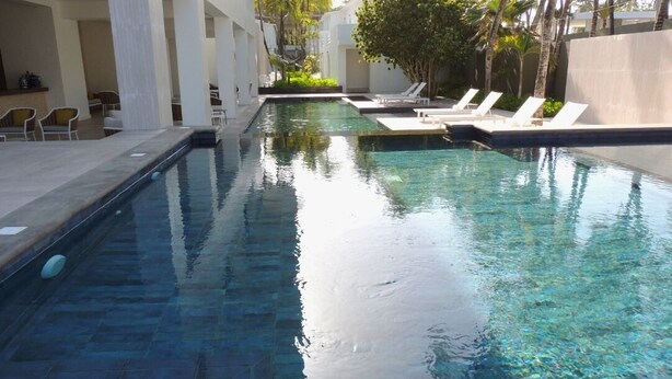 A swimming pool with lounge chairs and a covered seating area. - Hotel Miragua Playa El Agua (Paraguachí)