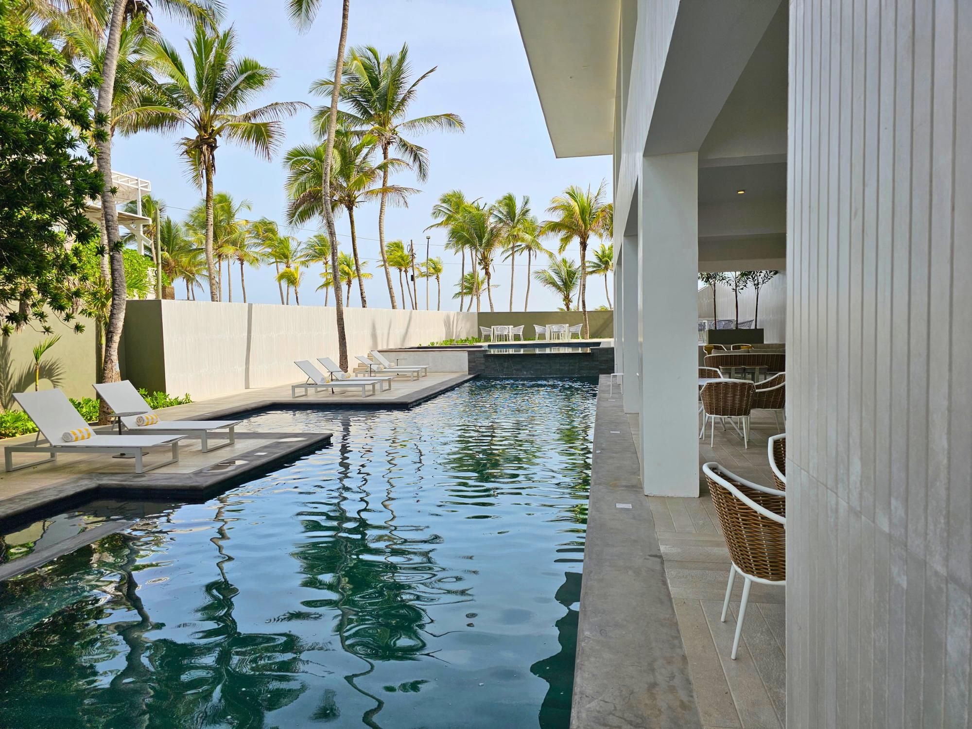 A swimming pool with lounge chairs and a view of palm trees.