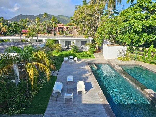 A pool area with a wooden deck, lounge chairs, and a clear blue pool. - Hotel Miragua Playa El Agua (Paraguachí)