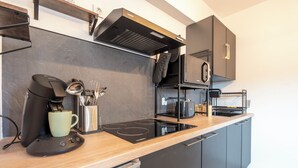 Una cocina moderna con estufa integrada, cafetera y microondas.