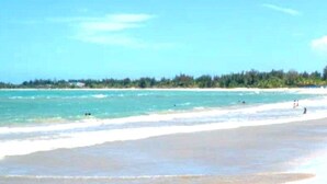Una playa con agua azul cristalina y una orilla arenosa.