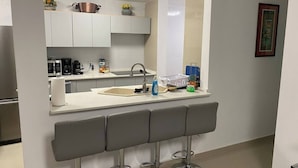 Una cocina moderna con una isla central, taburetes de bar, un lavamanos y una cafetera.