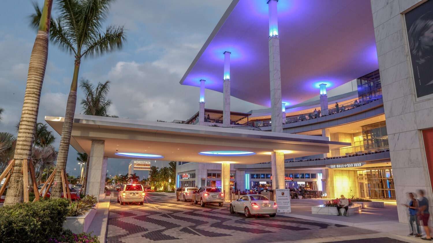 A multi-story hotel with a modern design, featuring a covered entrance, multiple floors, and a well-lit atrium.