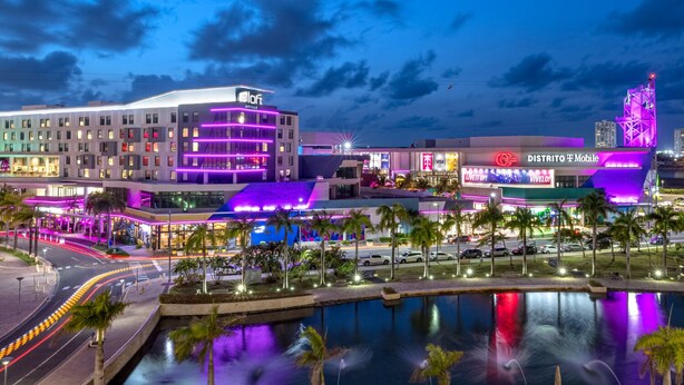 Un hotel con diseño moderno, que cuenta con una zona de piscina y un llamativo letrero de T-Mobile.