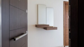 Ein modernes Zimmer mit einem Holzschrank, einem Spiegel auf einer Wandablage und einer Holztür.