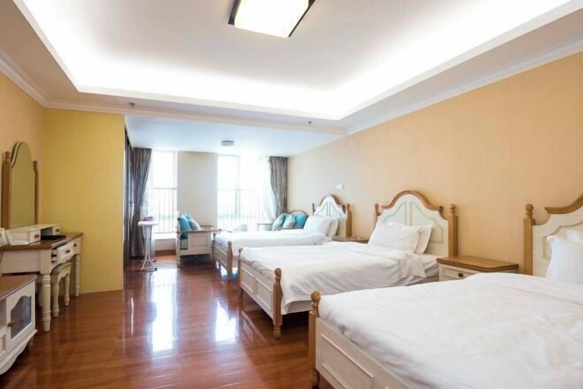 Une chambre d’hôtel avec trois lits, un bureau et une chaise.