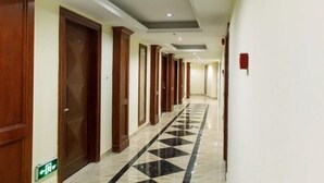 A hotel corridor with wooden doors, a checkered floor, and recessed ceiling lighting. - Hemu International Apartment (Guangzhou)