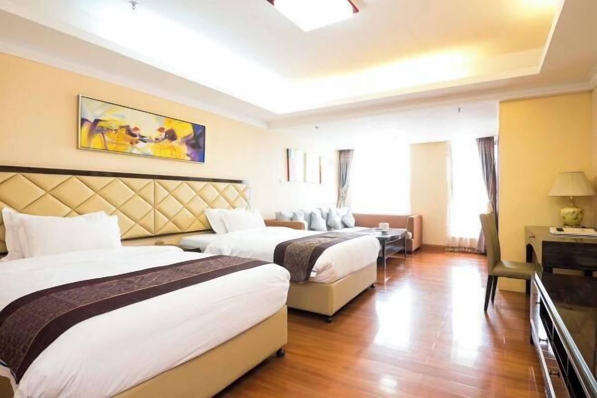 Une chambre d’hôtel avec deux lits, un canapé, un bureau et un tableau au mur.