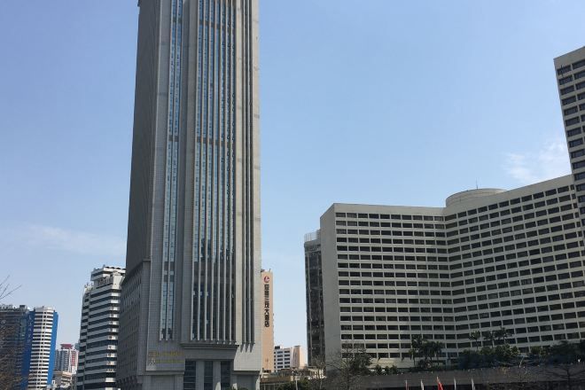 Un edificio alto y moderno con fachada de vidrio, rodeado de otros rascacielos.