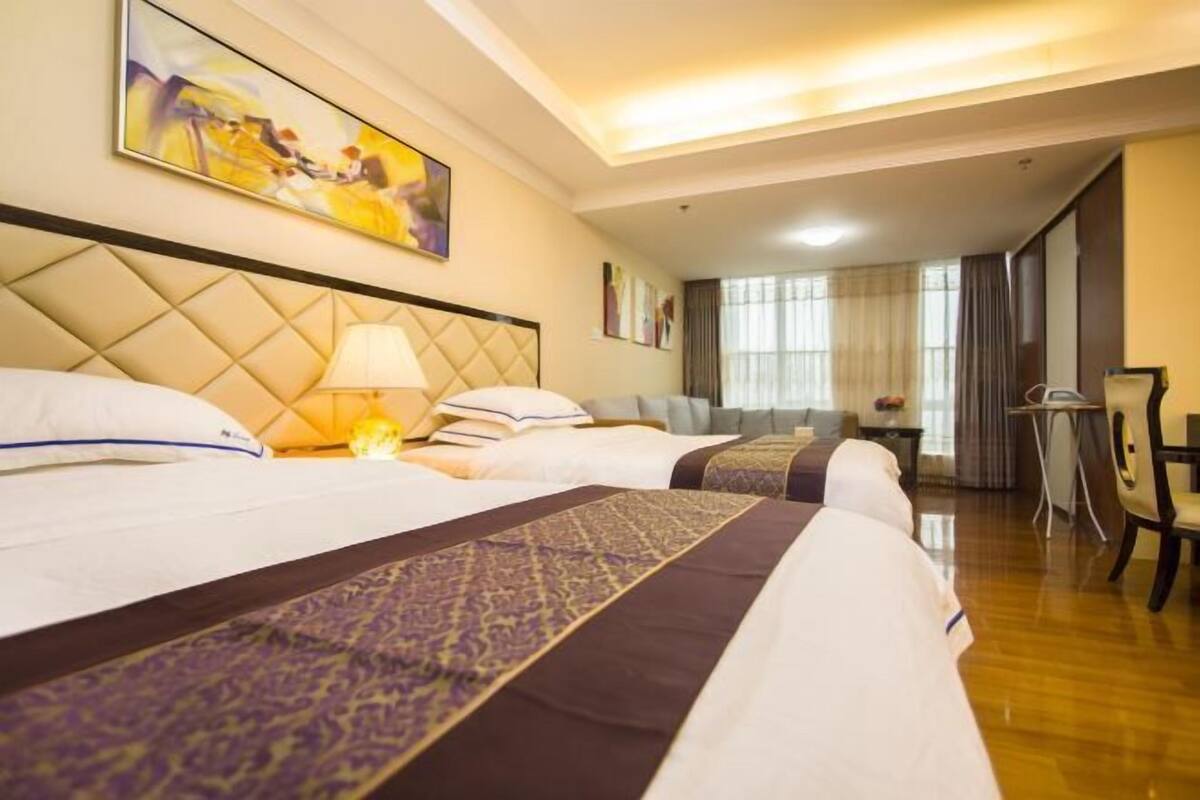 Une chambre d’hôtel avec un grand lit, un bureau, une chaise et un tableau au mur.