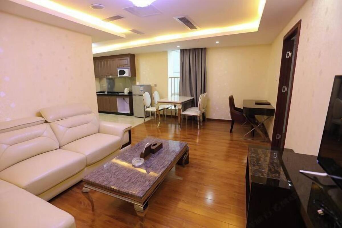 Un salon moderne avec un canapé, une table basse et un téléviseur. Il y a également un coin repas avec une table et des chaises.