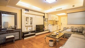 A modern living room with a sofa, coffee table, and a television. - Hemu International Apartment (Guangzhou)