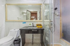 A bathroom with a toilet, sink, mirror, and shower.