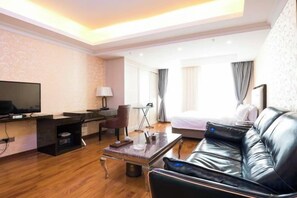 A hotel room with a bed, a desk with a computer, a television, and a leather sofa. - Hemu International Apartment (Guangzhou)